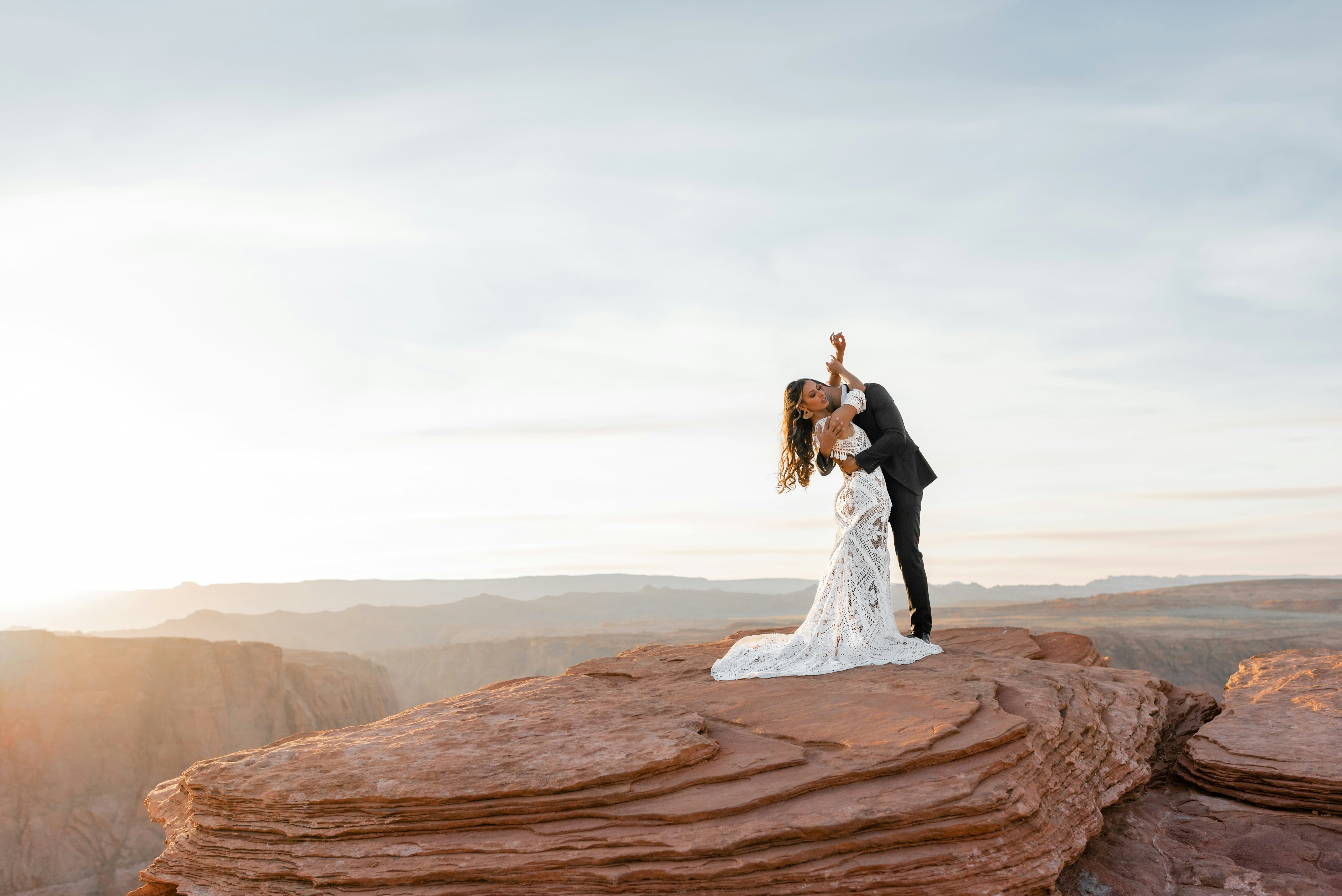 Un couple hétéro en tenue de mariage, s'enlaçant au sommet d'une montagne
